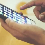 Hand tapping app icons on a smartphone screen, representing free productivity apps