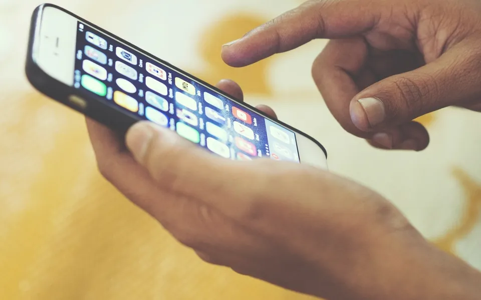 Hand tapping app icons on a smartphone screen, representing free productivity apps