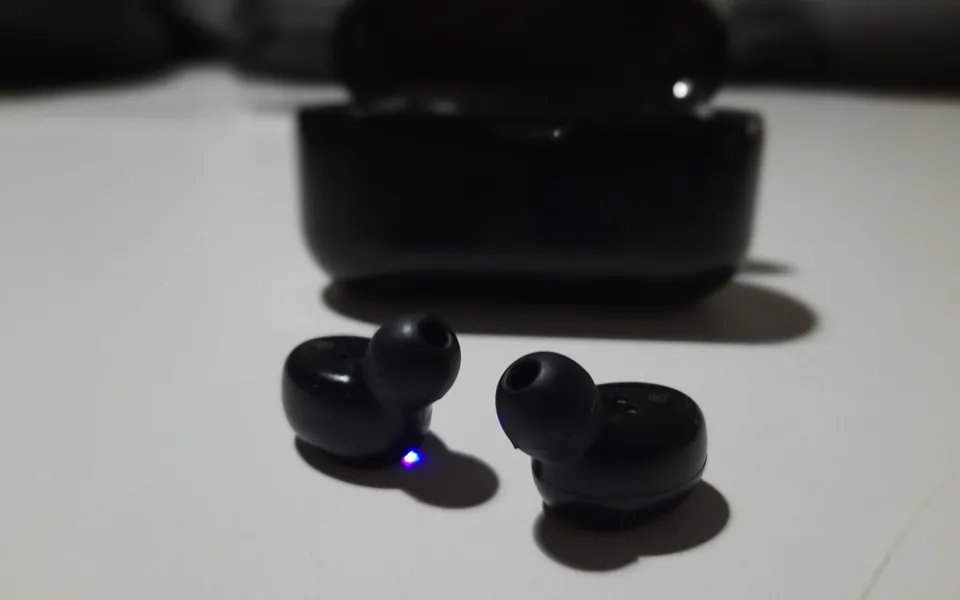 Pair of wireless earbuds next to their charging case