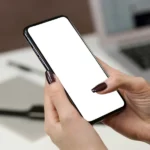 Person holding a smartphone near a laptop, illustrating passkey sign-in