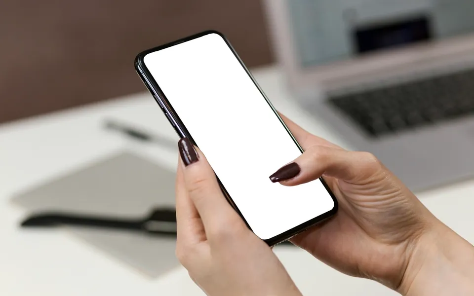 Person holding a smartphone near a laptop, illustrating passkey sign-in
